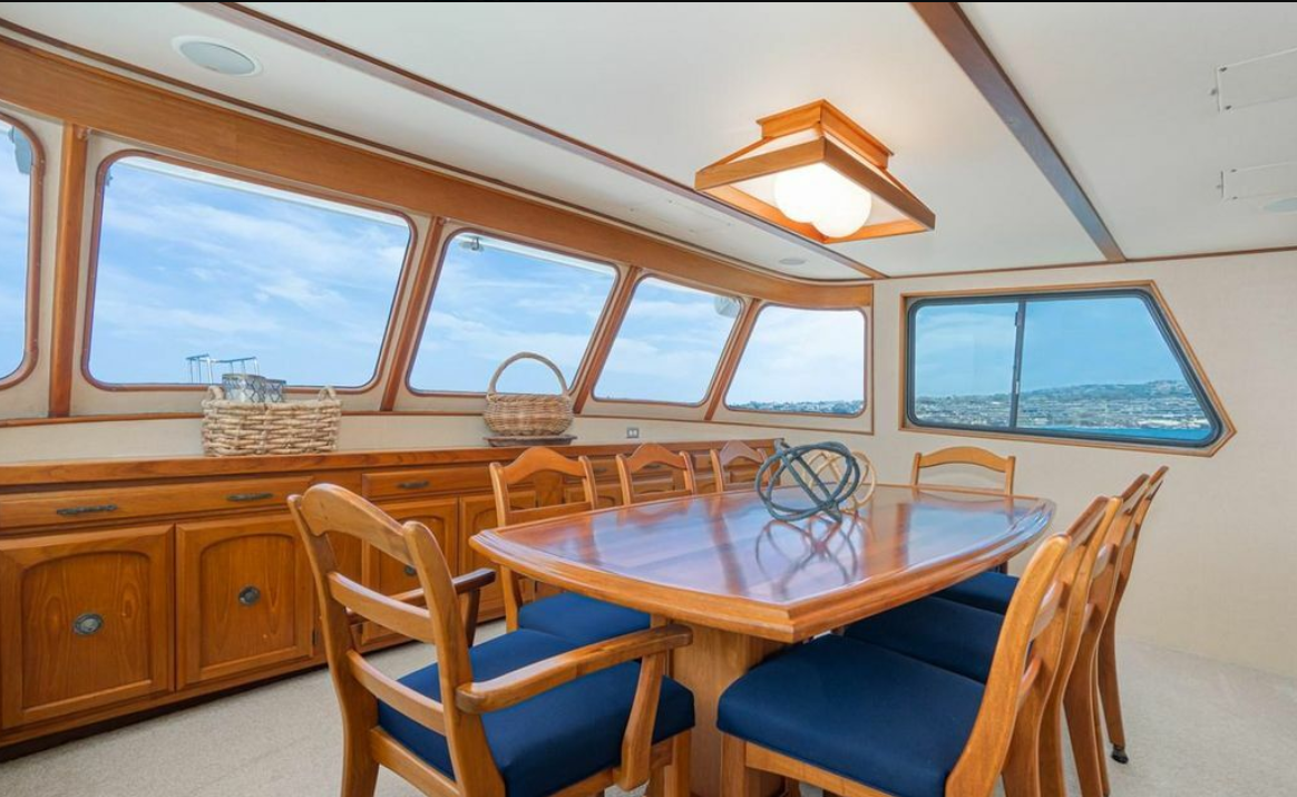 Forward dining area with teak table and panoramic windows aboard M/Y Oceana